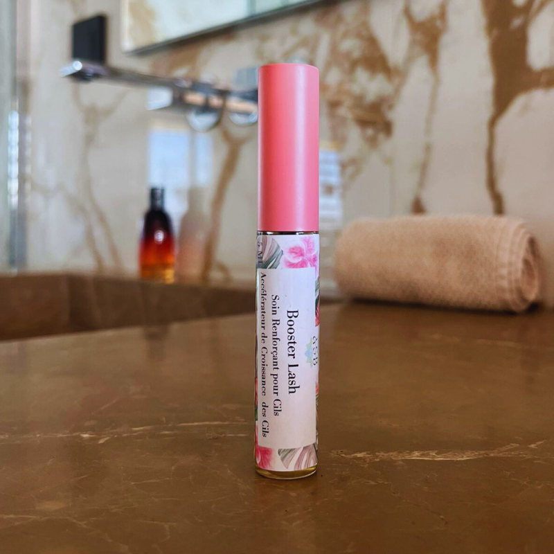 flacon en verre d'un booster lash soins renforçant pour les cils en gros plans poser sur le plans de travail en pierre dans une salle de bain 