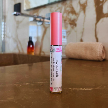 flacon en verre d'un booster lash soins renforçant pour les cils en gros plans poser sur le plans de travail en pierre dans une salle de bain 