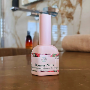 flacon en plastique d'un booster nails rose, accélérateur de croissance des ongles poser sur le plans de travail d'une salle de bain 