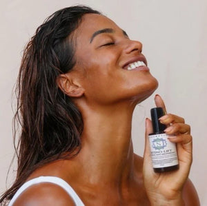 femme de profil souriant en gros plans avec le retino-lift dans sa main gauche 